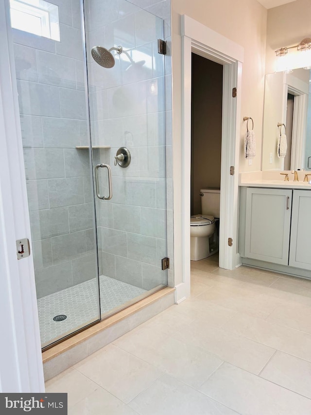 bathroom with tile patterned floors, toilet, a shower with door, and vanity