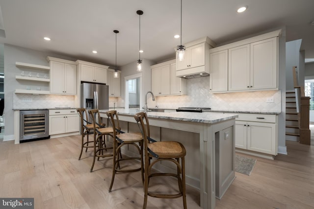 kitchen with a wealth of natural light, beverage cooler, decorative light fixtures, and light hardwood / wood-style floors