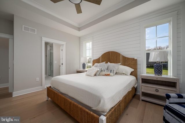 bedroom featuring wood walls, wood-type flooring, connected bathroom, and ceiling fan