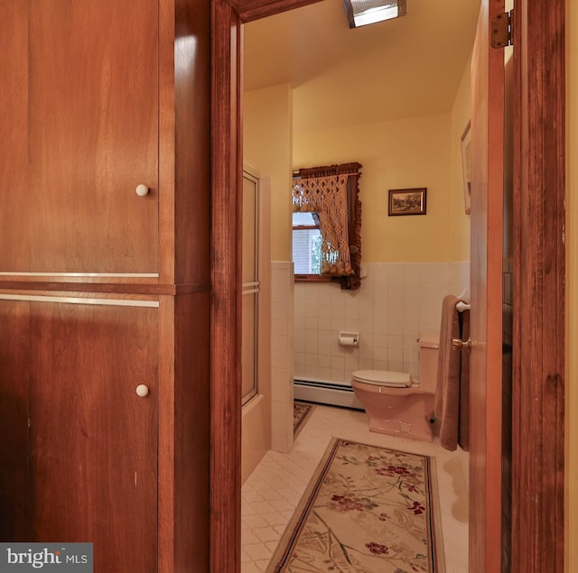 bathroom with tile flooring, tile walls, shower / bath combination with glass door, a baseboard radiator, and toilet