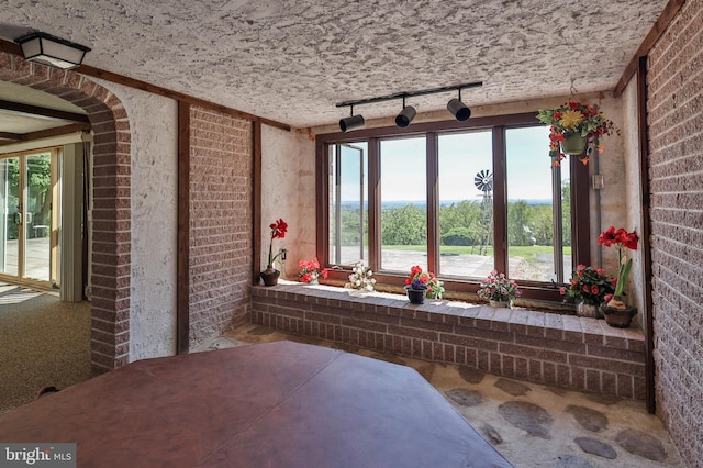 interior space with plenty of natural light, brick wall, and track lighting