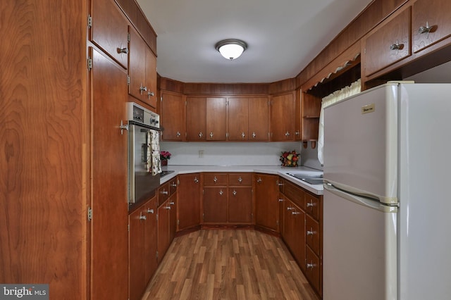 kitchen with oven, light hardwood / wood-style flooring, sink, and white refrigerator