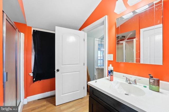 bathroom with vanity, lofted ceiling, walk in shower, and hardwood / wood-style floors