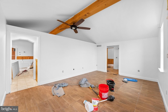 interior space featuring ceiling fan, vaulted ceiling with beams, light tile patterned flooring, and connected bathroom