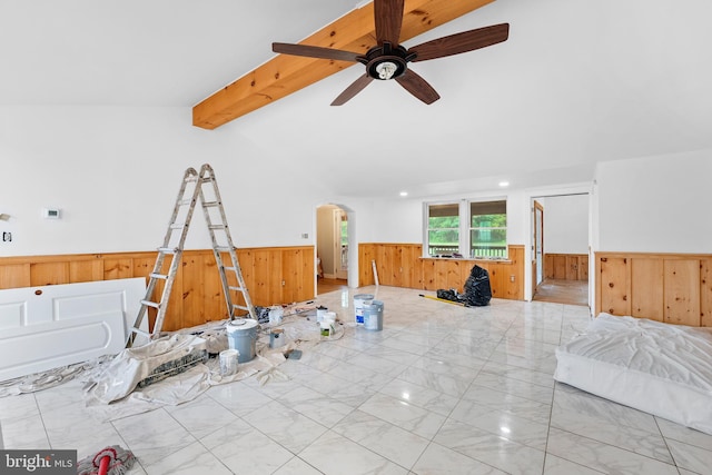 unfurnished living room with wooden walls, lofted ceiling with beams, and ceiling fan