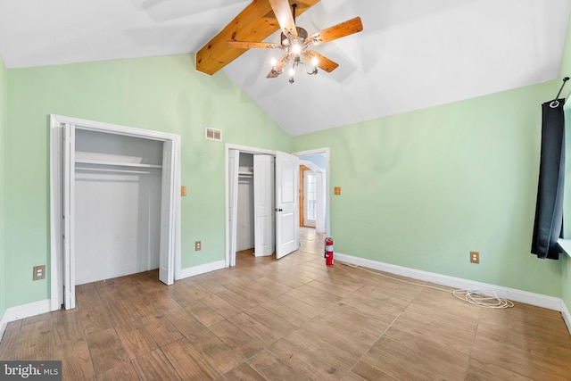 unfurnished bedroom with light hardwood / wood-style flooring, vaulted ceiling with beams, ceiling fan, and two closets