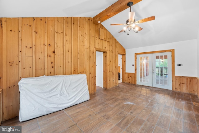 interior space featuring vaulted ceiling with beams, wooden walls, ceiling fan, and french doors