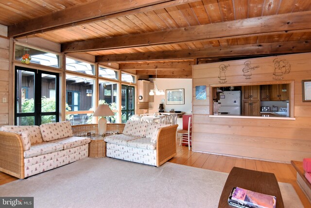 living room with wooden walls, light hardwood / wood-style flooring, beamed ceiling, wooden ceiling, and a notable chandelier