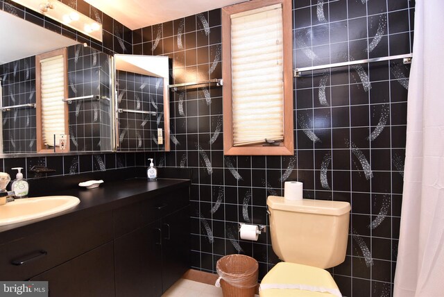 bathroom with tile walls, toilet, vanity, and tile flooring