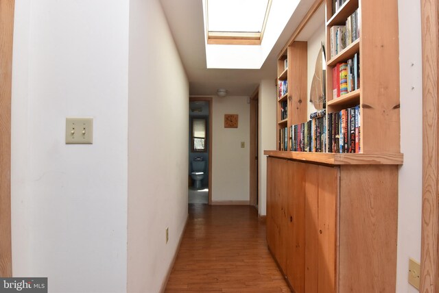 hallway featuring light hardwood / wood-style flooring and a skylight