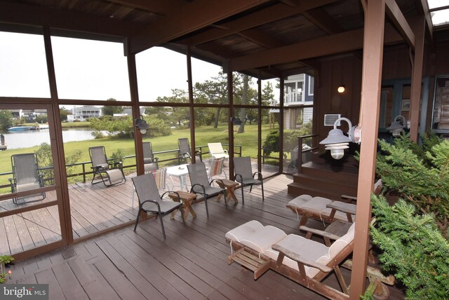 wooden terrace featuring a water view and a lawn