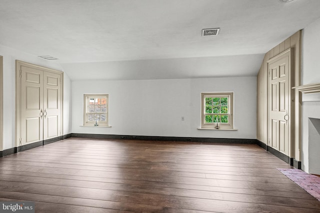 unfurnished living room featuring vaulted ceiling and dark wood-type flooring