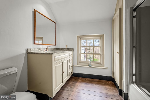 bathroom featuring toilet, vanity, vaulted ceiling, and hardwood / wood-style flooring