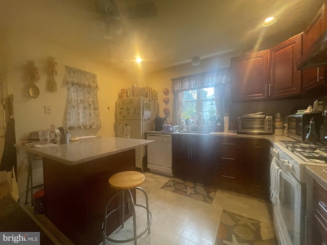 kitchen featuring a breakfast bar area, white gas range, dishwashing machine, and custom exhaust hood