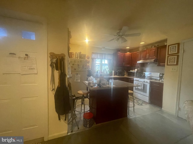 kitchen featuring range with two ovens, ceiling fan, and a breakfast bar