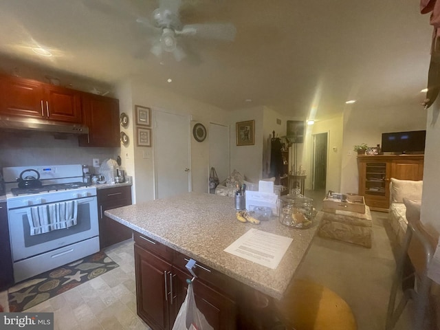 kitchen featuring light tile flooring, light stone countertops, white range with gas cooktop, and ceiling fan