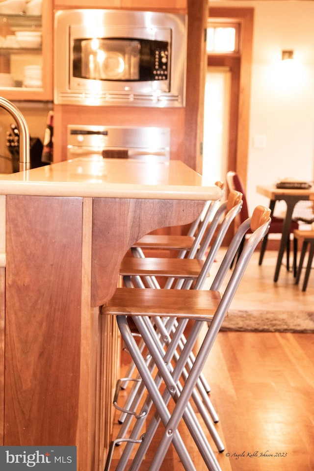 interior space with range, stainless steel microwave, and light wood-type flooring