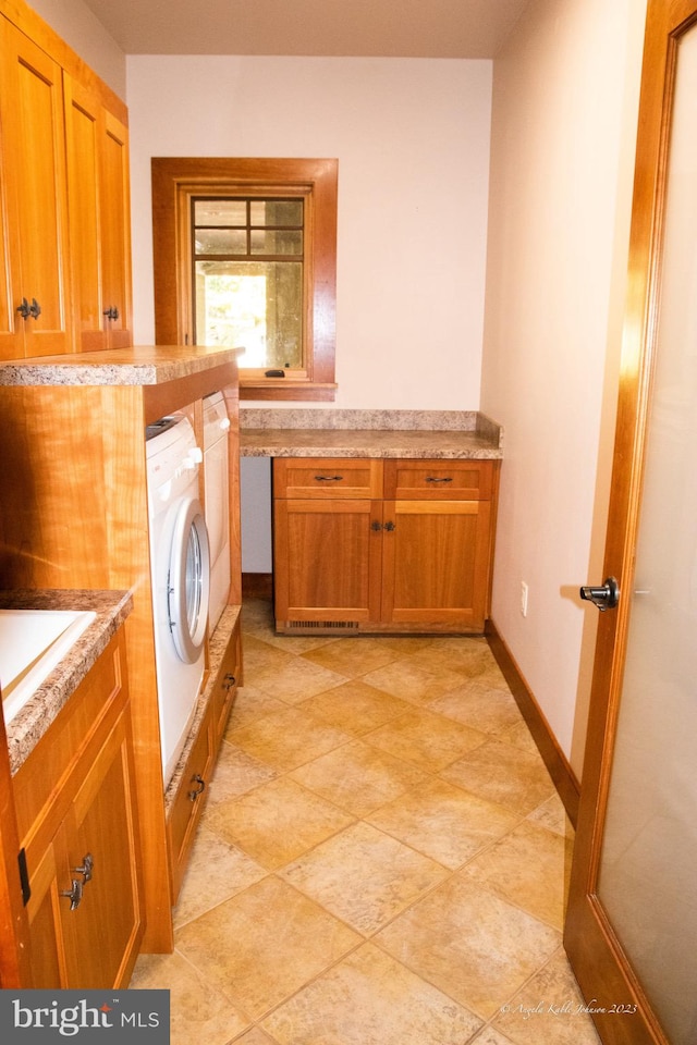 washroom featuring washer and dryer, light tile floors, and cabinets