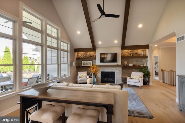 living room with beamed ceiling, high vaulted ceiling, ceiling fan, light hardwood / wood-style flooring, and a fireplace