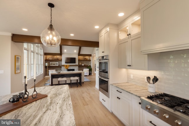 kitchen featuring light hardwood / wood-style floors, stainless steel appliances, decorative light fixtures, white cabinetry, and light stone counters