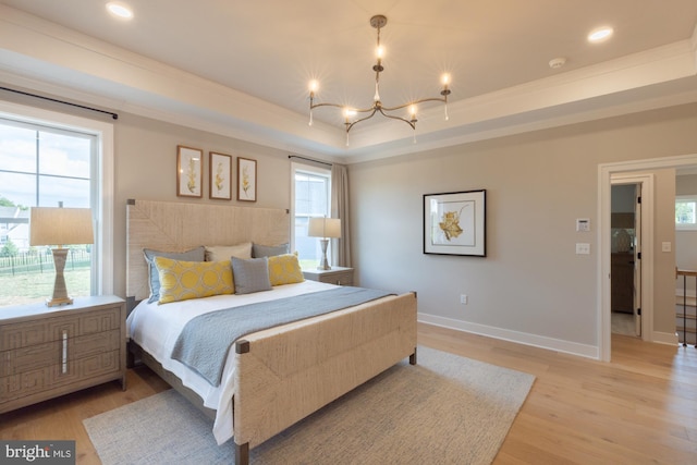 bedroom featuring a raised ceiling, light wood-type flooring, and an inviting chandelier