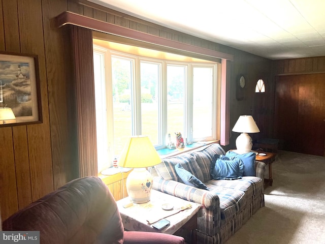 living room featuring a healthy amount of sunlight, wooden walls, and carpet flooring