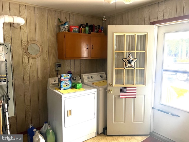 washroom with cabinets, wooden walls, washer and dryer, and light tile patterned floors