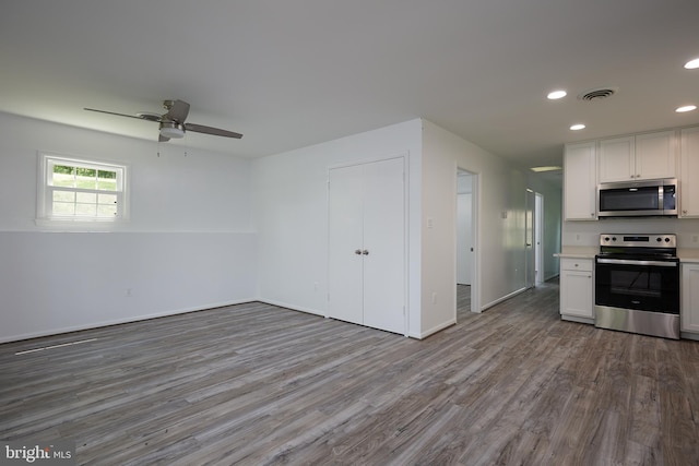 kitchen with white cabinets, ceiling fan, appliances with stainless steel finishes, and hardwood / wood-style flooring