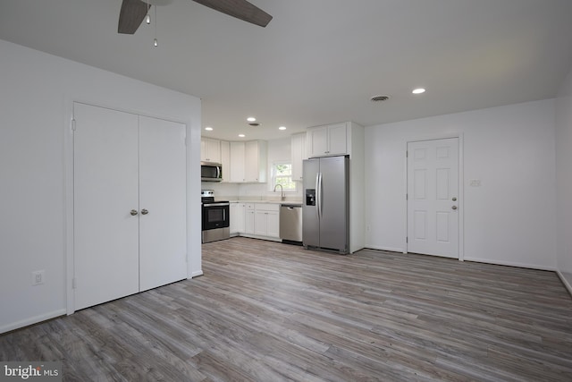 kitchen with ceiling fan, appliances with stainless steel finishes, light hardwood / wood-style floors, sink, and white cabinets