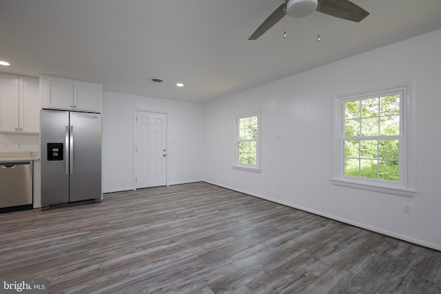 kitchen featuring hardwood / wood-style floors, stainless steel appliances, ceiling fan, and white cabinets