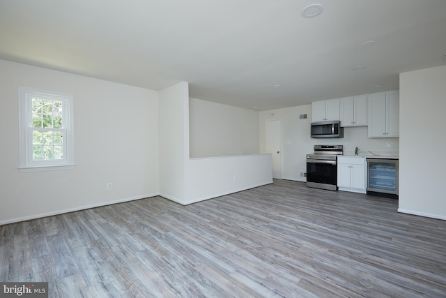 unfurnished living room with beverage cooler, light hardwood / wood-style flooring, and sink