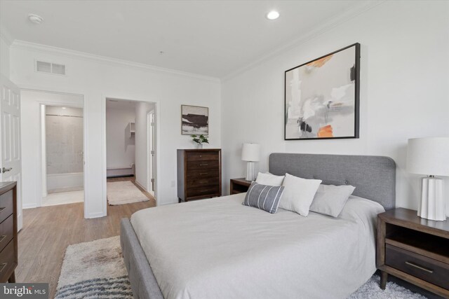 bedroom with light hardwood / wood-style flooring, ornamental molding, and ensuite bath