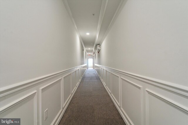 hallway with dark colored carpet and crown molding