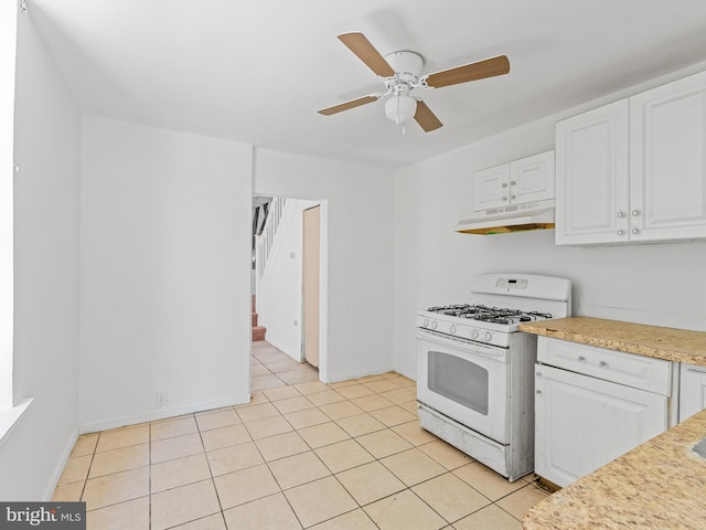 kitchen featuring light tile flooring, white range with gas cooktop, ceiling fan, and white cabinetry