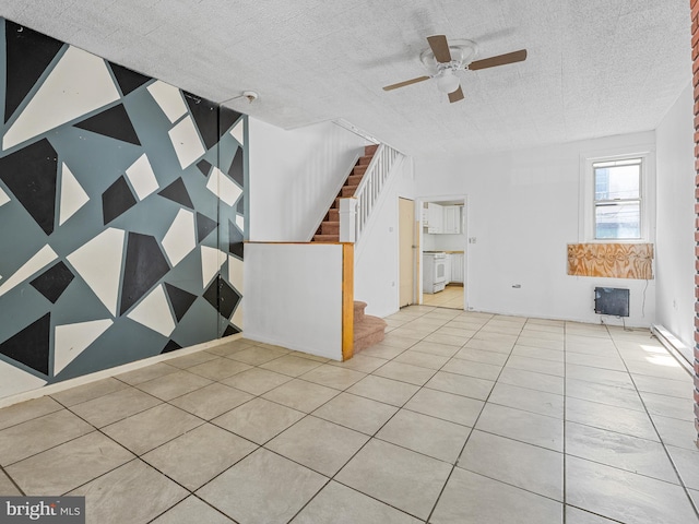 interior space with ceiling fan, light tile floors, and a textured ceiling