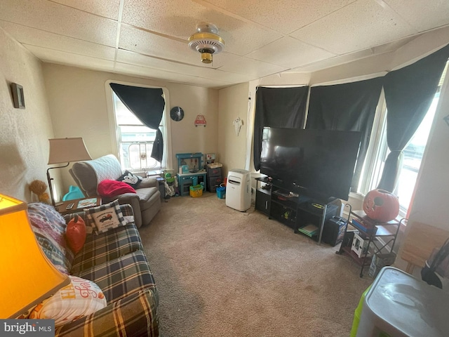 living room featuring a drop ceiling and carpet floors