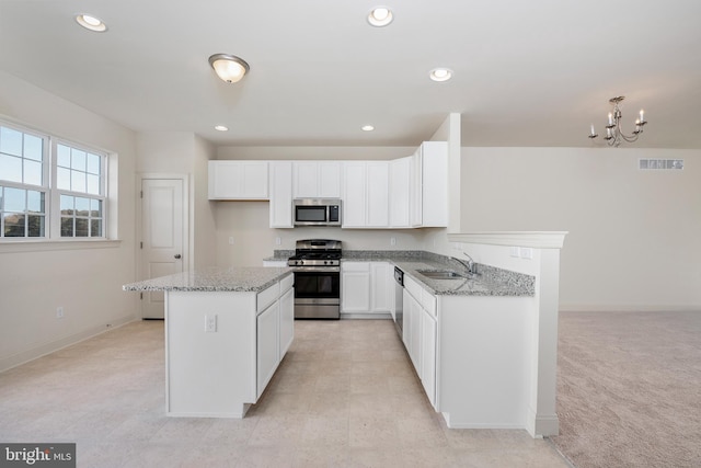 kitchen with white cabinetry, a notable chandelier, appliances with stainless steel finishes, sink, and light stone counters