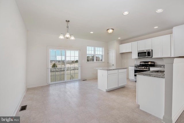 kitchen featuring appliances with stainless steel finishes, a chandelier, stone counters, decorative light fixtures, and white cabinetry