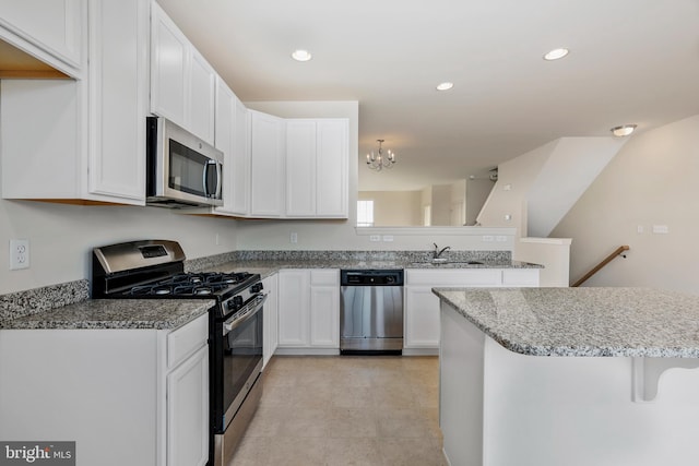 kitchen featuring an inviting chandelier, stainless steel appliances, light tile floors, sink, and white cabinetry