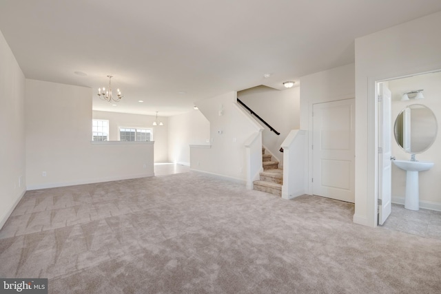 unfurnished living room featuring sink, a chandelier, and light colored carpet