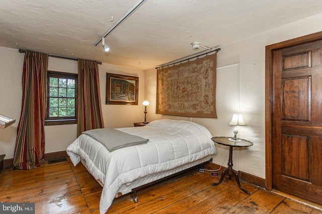 bedroom featuring hardwood / wood-style floors and track lighting