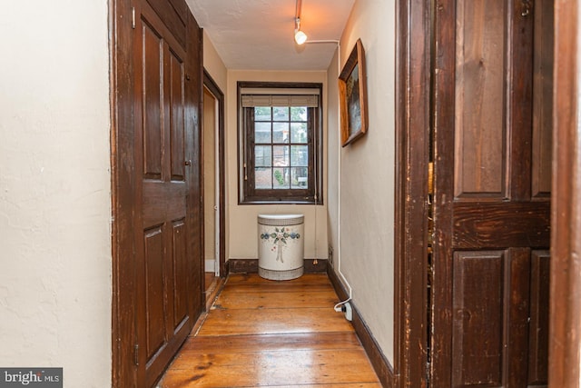 hall with rail lighting and hardwood / wood-style floors