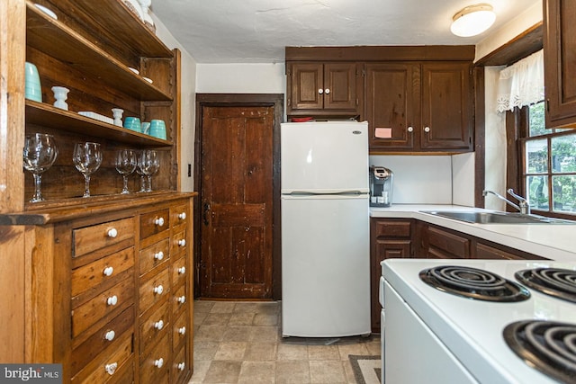 kitchen with light tile floors, stove, white fridge, and sink