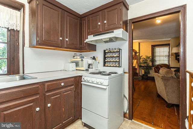 kitchen featuring light tile floors, dark brown cabinetry, white appliances, and sink