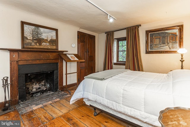 bedroom with track lighting and dark wood-type flooring