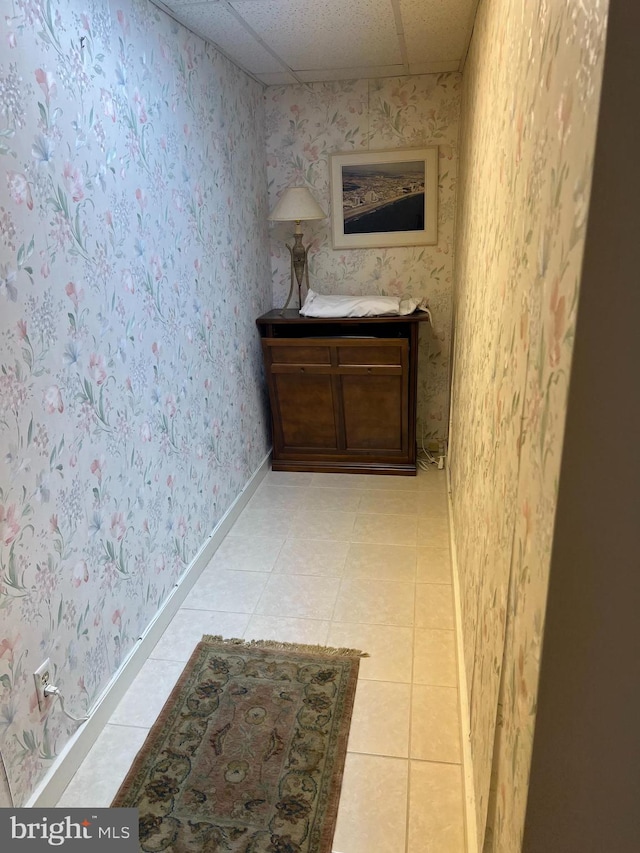 hallway featuring a drop ceiling and light tile patterned floors