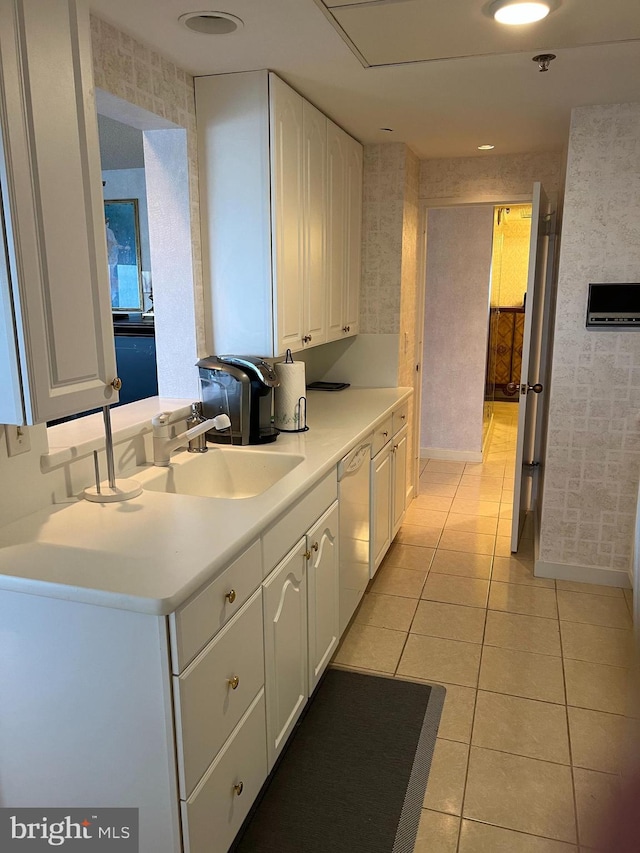 kitchen with dishwasher, sink, white cabinets, kitchen peninsula, and light tile patterned floors