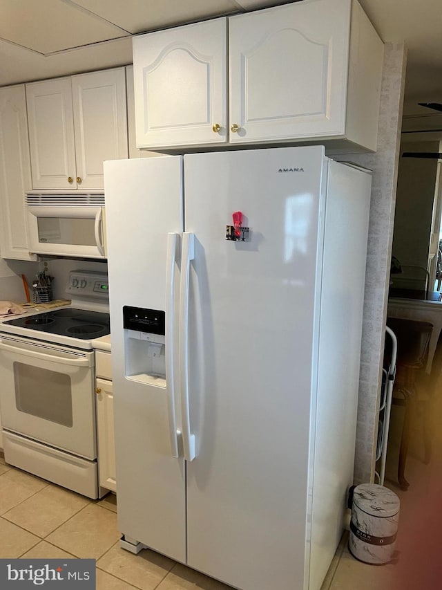 kitchen featuring white appliances, white cabinetry, and light tile patterned flooring