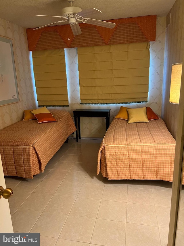 tiled bedroom with ceiling fan and a textured ceiling