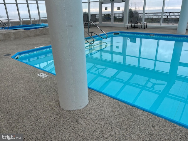 view of swimming pool featuring glass enclosure